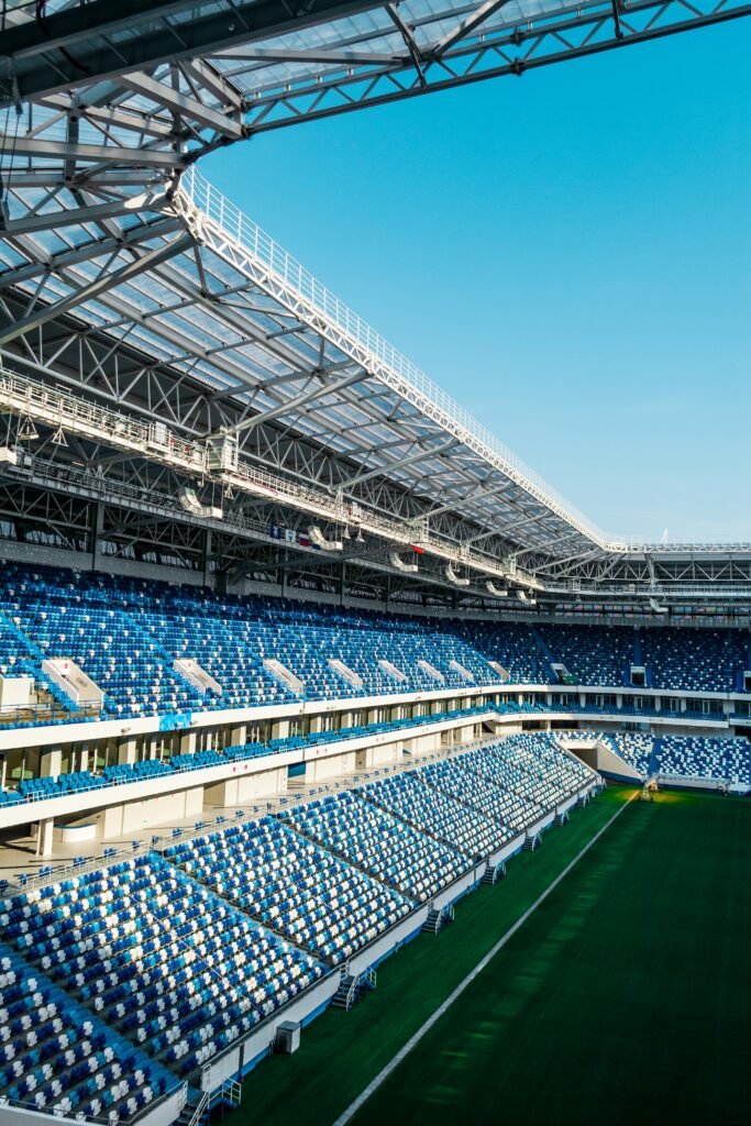 Spacious modern soccer stadium with blue seating and open sky view.